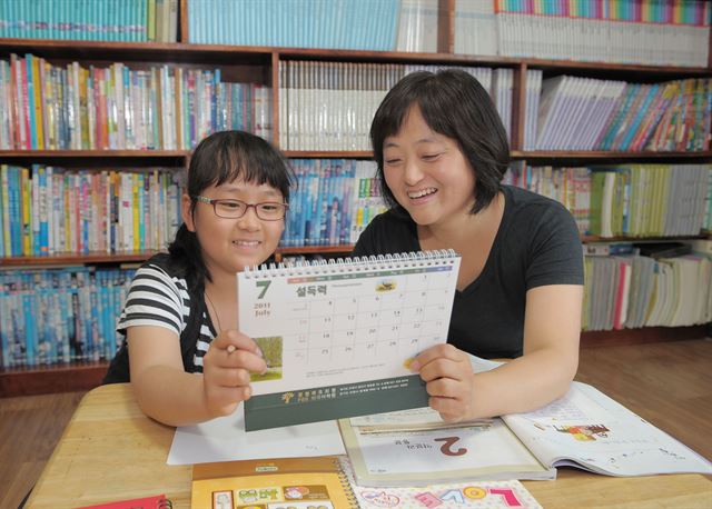 한 초등학생이 엄마와 함께 달력을 들고 공부 계획을 세우고 있다. 계획을 달성할 때마다 학생이 느끼는 성취감은 학습성과 향상에 큰 도움이 된다. 한국일보 자료사진