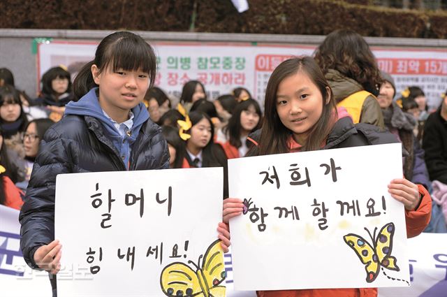 위안부 피해를 알리기 위한 전시회를 준비 중인 고혜원(왼쪽)ㆍ혜민 자매가 21일 서울 중학동 일본 대사관 앞에서 열린 일본군 위안부 문제 해결을 위한 수요집회에 참석해 직접 만든 피켓을 들고 있다. 이정현 인턴기자 (국민대 사법학과 3)