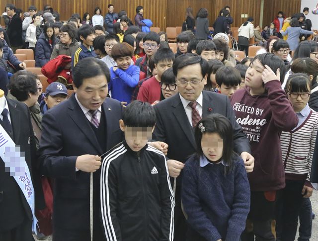 박수범(왼쪽) 대전 대덕구청장과 이승호 경북한의원장이 29일 구청 강당에서 열린 '2015학년도 대덕장학생 교복맞춤 전달식'에서 학생들의 어깨 폭을 줄자로 재고 있다.