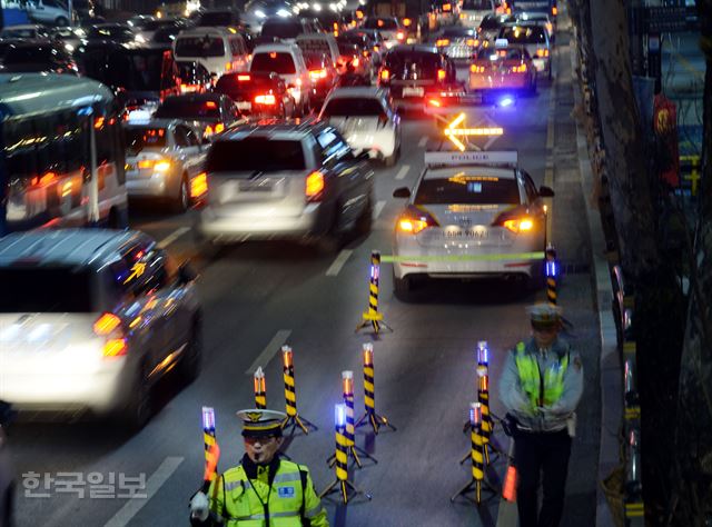 지난 10일 저녁 서울 사당동 왕복 8차선 도로에서 서울 관악경찰서 소속 경찰관들이 리프트경광등 순찰차를 세워 둔 채 교통지도 업무를 하고 있다. 순찰차 앞에 놓인 얇은 철제 기둥들은 안전경고등으로, 리프트경광등과 함께 2차 사고 방지를 위한 장비다. 신상순 선임기자ssshin@hk.co.kr