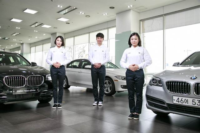 BMW코리아가 자동차 업계 최초로 운영 중인 제품 설명 전문 요원인 프로젝트지니어스(PG) 1기 생들인 류보라, 김홍일, 전윤희씨가 13일 서울 양재동 도이치모터스 양재전시장에서 정장 대신 캐주얼 차림으로 차량 앞에 서 있다. BMW코리아 제공