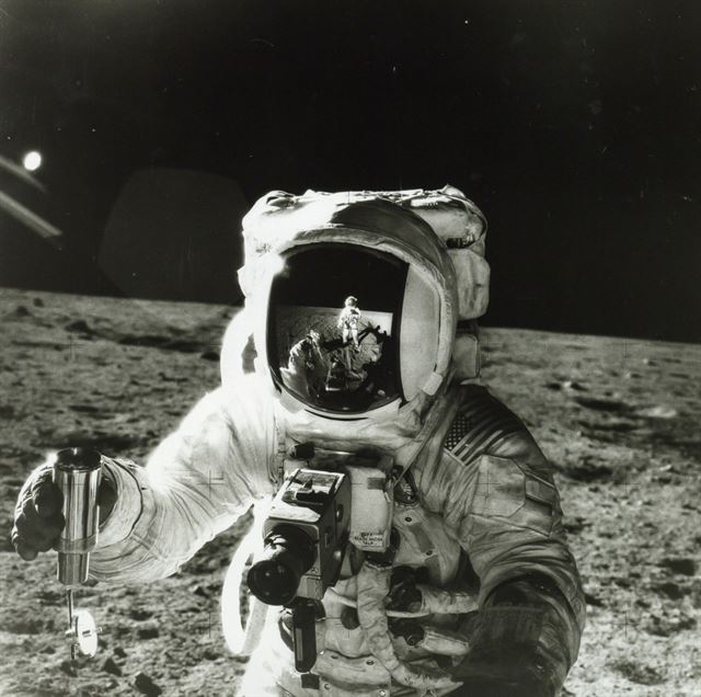 Alan Bean holds a container of lunar soil with the reflection of Pete Conrad in his visor in 1969. 사진= Dreweatts & Bloomsbury Auctions .