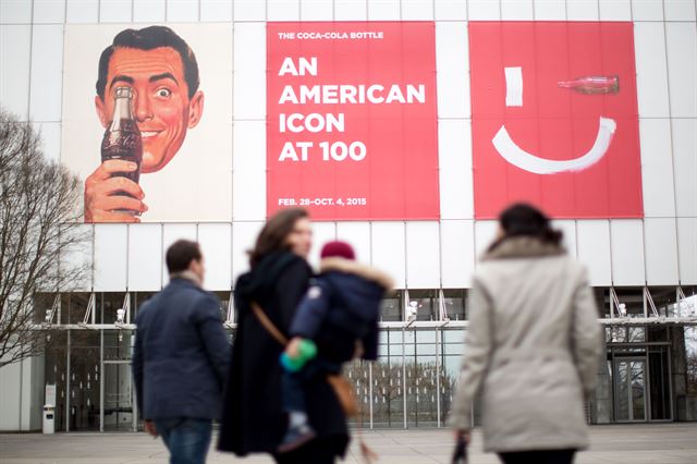 코카콜라 병 탄생 100주년을 앞두고 미 조지아주 애틀랜타 소재 '하이 미술관'(High Museum)에 25일(현지시간) 시민들이 전시회 현수막이 걸린 박물관 앞을 걸어가고 있다. AP 연합뉴스