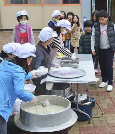 경남 지역의 무상급식 중단 첫 날인 1일 진주 지수초등학교 학부모들이 학교 건물 뒤편에 솥 등 조리시설을 설치한 뒤 학생들의 점심 식사를 직접 만들어 배식하고 있다. 이 학교 학부모회 소속 학부모 15명은 경남도의 무상급식 지원 중단에 항의하는 뜻에서 닭백숙을 만들어 자녀들에게 먹였다. 진주=전혜원기자 iamjhw@hk.co.kr