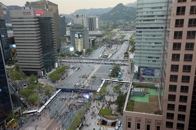 ‘세월호 1주년’ 이후 첫 주말을 맞은 18일 오후 ‘세월호참사 범국민대회’ 참가자들이 광화문 광장에서 세월호 참사 진실규명 등을 촉구하고 있다. 광장 주변이 경찰 차량들로 만들어진 ‘차벽’에 둘러싸여 있다. 연합뉴스