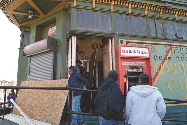 28일 오전 볼티모어시 주민들이 전날 폭도들의 약탈로 피해를 입은 ‘옥스퍼드 테번’을 청소하고 있다.