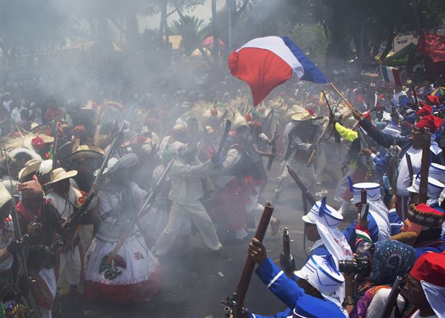 멕시코 수도 멕시코 시티 5일(현지시간) 1862년 5월 '싱코 데 마요'(Cinco de Mayo) 축제가 열린 가운데 멕시코군 복장을 한 이들과 프랑스군 복장을 한 이들이 전투 장면을 재연하고 있다. 스페인어로 마요는 5월, 싱코는 5일을 뜻한다. 싱코 데 마요는 1862년 5월 5일 멕시코 군대가 프랑스 군대를 기적적으로 물리친 날을 기념하는 행사이다. 멕시코 시티=AP 연합뉴스