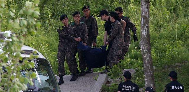 13일 오전 예비군 사격훈련중 총기 사망사고가 발생한 예비군 훈련장에서 군 관계자들이 총기를 난사하고 자살한 예비군의 시신을 들고 이동하고 있다. 연합뉴스