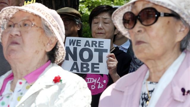 20일 오후 서울 종로구 중학동 일본대사관에서 열린 ‘제1,178차 일본군 위안부 문제해결을 위한 정기 수요시위’에 참석한 한 일본인이 길원옥(왼쪽), 김복동 할머니 뒤에서 ‘우리는 아베가 아니다’라고 적힌 손팻말을 든 채 눈을 감고 있다. 연합뉴스