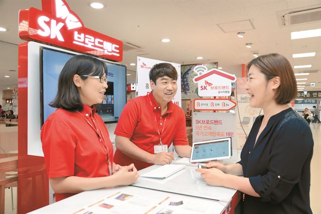 서울 가양동 이마트에 마련된 SK브로드밴드 판매대를 찾은 여성이 통신 상품 설명을 듣고 있다. SK브로드밴드 제공