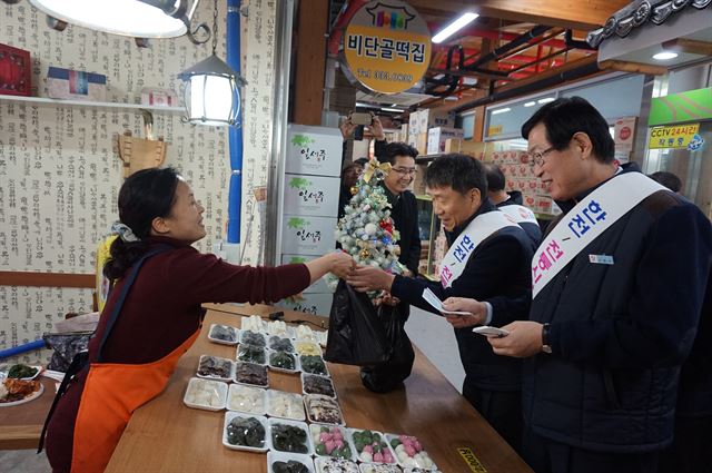 조환익(맨 오른쪽) 한국전력 사장과 임직원들이 빛가람 혁신도시 인근의 나주 목사고을 전통시장을 찾아 떡을 구입하며 상인과 대화를 나누고 있다. 한전 제공