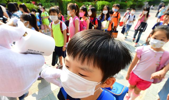 메르스(MERS·중동호흡기증후군) 여파로 휴업을 실시했던 경기 수원의 한 초등학교에서 등교가 재개된 15일 오전 학생들이 학교입구에서 체온을 재고 있다. 이 학교는 메르스 전문병원인 경기도의료원 수원병원 인근에 위치해 있다. 수원=뉴시스