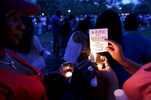 18일(현지시간) 총기난사 사고가 발생한 미 사우스캐롤라이나주 찰스턴의 '이매뉴얼 아프리칸 감리교회' 부근 매리언 광장에 모인 시민들이 희생자들을 추모하며 촛불집회에 참석해 촛불을 밝히고 있다. 찰스턴=AP 연합뉴스