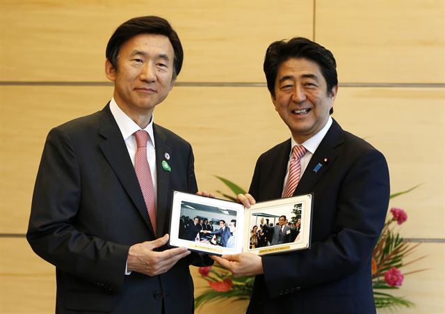 일본을 방문 중인 윤병세 외교장관이 22일(현지시간) 일본 도쿄의 아베총리공관에서 아베 신조 일본 총리와 회동에 앞서 아베 총리의 선친인 아베 신타로(전 외교장관)의 사진을 선물로 전한후 함께 들어보이고 있다. 도쿄=AP 연합뉴스