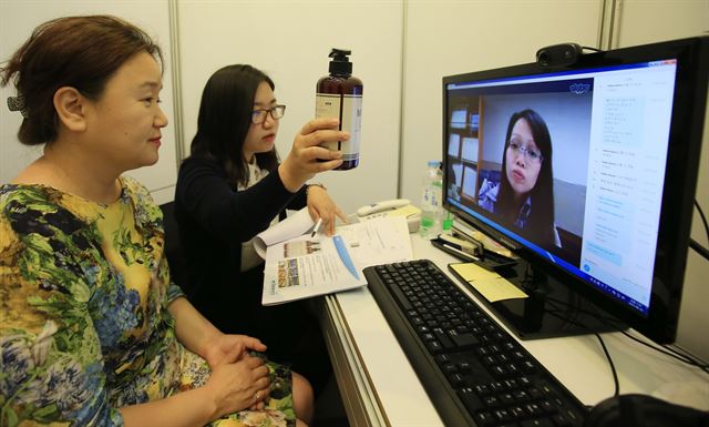 생활용품 판매업체인 더블유타노시의 고혜주(왼쪽) 해외사업부장이 25일 서울 염곡동 대한무역투자진흥공사(KOTRA) 외국기업창업지원연구센터(IKP)에서 샴푸를 수출하기 위해 화면 속 베트남 하노이의 바이어에게 제품 설명을 하고 있다. 연합뉴스