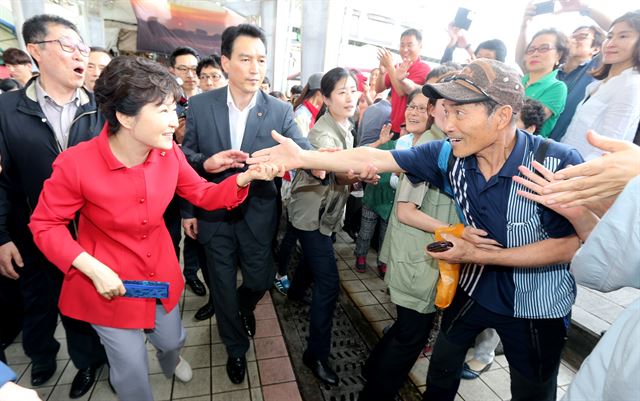 26일 창조경제혁신센터 출범식 참석차 제주를 방문한 박근혜 대통령이 동문시장을 지나던 중 환영나온 시민이 내민 손을 반갑게 잡고 있다. 제주=연합뉴스