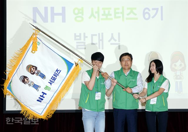 'NH 영 서포터즈' 6기 발대식에 김정식 부회장(가운데)과 학생대표가 기를 흔들고 있다./홍인기기자 hongik@hankookilbo.com