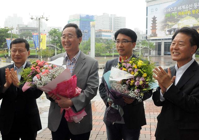 7일 독일에서 열린 세계유산 등재회의 출장을 마치고 돌아온 송하진(왼쪽에서 두 번째) 전북도지사 일행이 도청 현관 앞에서 직원의 꽃다발을 받고 익산 백제역사유적지구의 세계유산 등재 기쁨을 나누었다. 전북도 제공