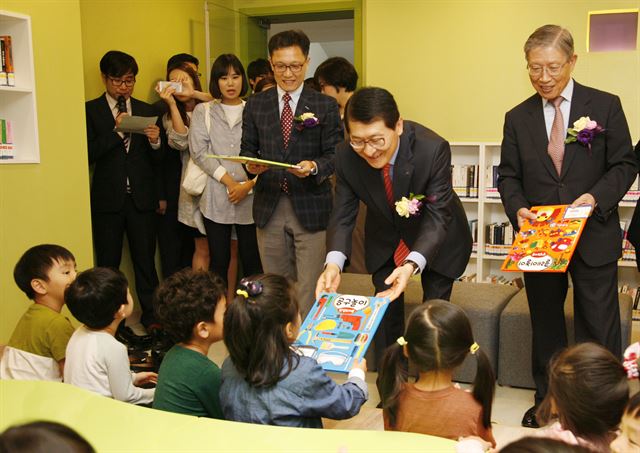 신한카드 위성호 사장(오른쪽에서 두 번째)이 신한카드의 기부금과 임직원, 고객들이 모은 성금으로 구축된 아름인 도서관에서 아이들에게 책을 전해 주고 있다. 신한카드 제공