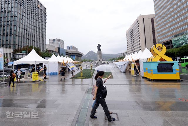 비가 내린 12일 새단장한 서울 광화문광장 세월호 농성장 앞으로 시민들이 지나가고 있다. 세월호 유가족과 시민단체들은 농성 1년을 맞아 ‘ㄷ’자 형태에서 가운데 공간을 터 시민들이 다닐 수 있게 농성장을 새단장했다. 홍인기기자 hongik@hankookilbo.com