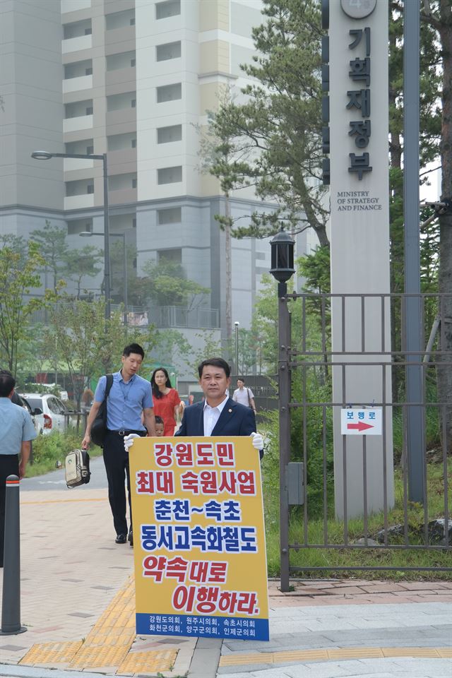 김시성 강원도의회 의장이 14일 오전 정부세종청사 기획재정부 정문 앞에서 대통령 공약사업인 춘천∼속초 동서고속화철도 조기 건설을 촉구하는 1인 시위를 하고 있다. 강원도의회 제공