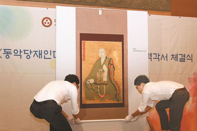 21일 서울 종로구 한국불교역사문화기념관에서 열린 동악당재인대선사진영 환수 공개식에서 관계자들이 그림을 공개하고 있다. 동악당재인대선사는 정유재란 이후 어지러워진 선암사의 승풍을 바로잡는데 기여한 인물로 전해진다. 대한불교 조계종 제공