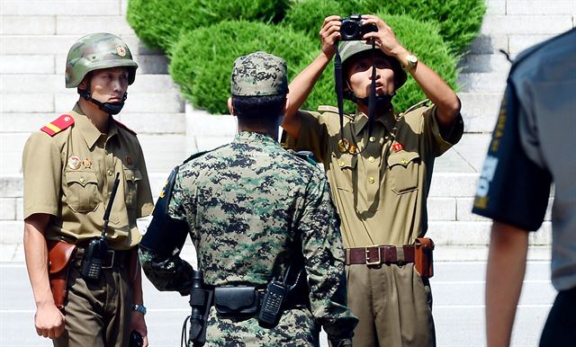 판문점 공동경비구역에서 근무 중인 북한 병사가 27일 우리 측 경비병 머리 위로 카메라를 들어 올려 사진을 찍고 있다. 당시 공동경비구역 남측에서는 정전협정 62주년 기념식을 마친 참전국 대표 등 참석자들이 북측을 배경으로 기념사진을 찍고 있었다. 사진공동취재단