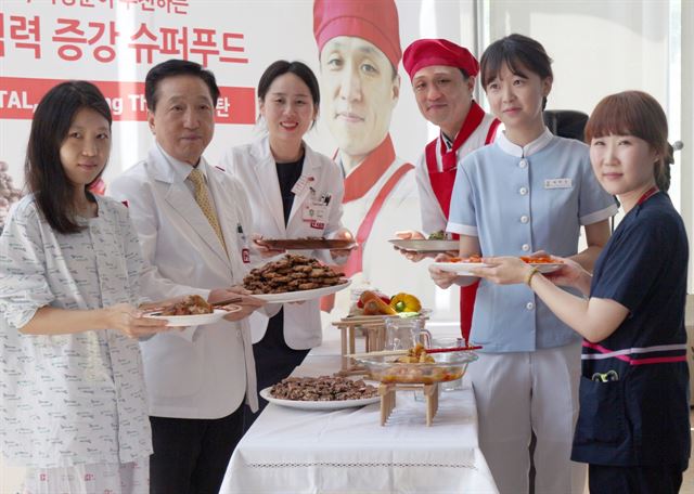 6일 에이치플러스 양지병원 로비에서 내분비내과 백혜리 과장이 추천한 식재료로 산부인과 전문의 이성훈 자궁근종센터장이 직접 요리한 레시피가 선 보이고 있다. 김철수 이사장(왼쪽 세번째),이성훈 산부인과 전문의(오른쪽 세번째), 백혜리 내분비내과 전문의(왼쪽 세번째). 에이치플러스 양지병원제공