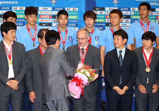 2015 동아시아축구연맹(EAFF) 축구선수권대회(이하 동아시안컵)에서 7년 만에 우승을 이끈 울리 슈틸리케 축구 국가대표팀 감독이 10일 오후 금메달을 목에 걸고 인천공항을 통해 입국해 축하 꽃다발을 받고 있다. 연합뉴스