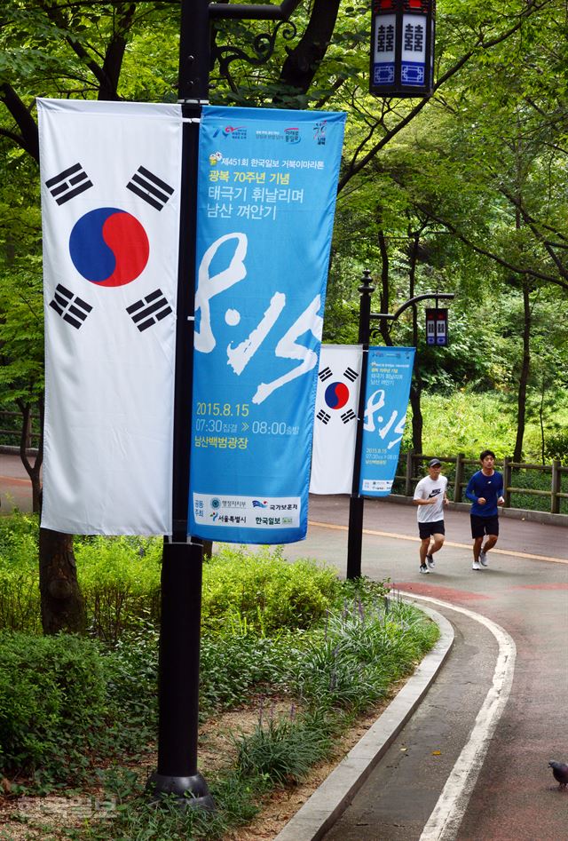 13일 서울 남산 순환도로에 광복 70주년을 맞아 나라사랑의 정신을 일깨우기 위해 한국일보, 행정자치부, 국가보훈처, 서울특별시가 함께 마련한 ‘태극기 휘날리며 남산 껴안기’ 행사 홍보 배너와 태극기가 나란히 걸려 있다. 신상순 선임기자 ssshin@hankookilbo.com