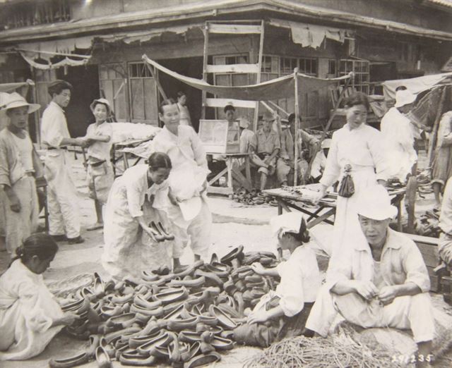 1947년 10월 도로 한편에 마련된 장터에서 한 여성이 짝이 맞는 신발을 찾고 있다. 고무신은 한국에서 수요가 매우 높았다. 국사편찬위원회 제공