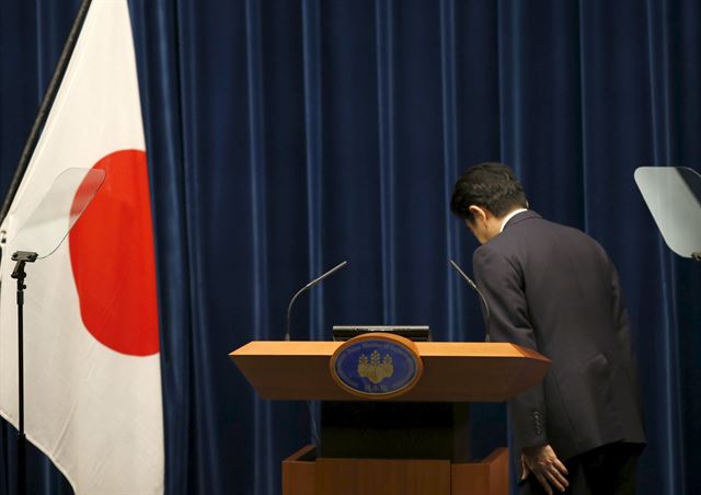 아베 신조 일본 총리가 14일 도쿄 총리관저에서 ‘전후 70주년 담화’를 발표하기에 앞서 국기에 예를 표하며 고개를 숙이고 있다. 도쿄=AP 연합뉴스