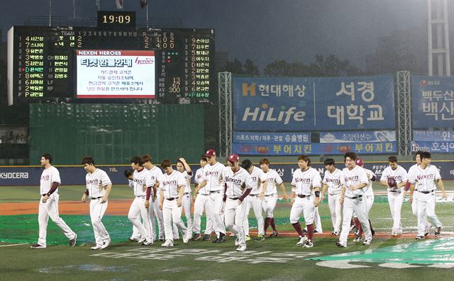 넥센 선수들이 지난 16일 목동구장에서 열린 롯데와의 경기에서 갑작스러운 폭우로 경기가 취소돼 그라운드를 벗어나고 있다. 연합뉴스