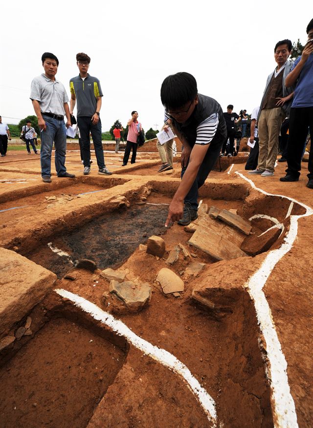 전용호(가운데) 국립부여문화재연구소 학예사가 백제 왕궁 부엌터로 추정되는 익산 왕궁리 유적을 설명하고 있다. 철제 솥과 불 피운 흔적인 벽체 등이 발굴됐다. 문화재청 제공