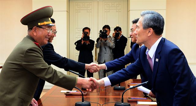 북한의 포격도발로 인한 대치상황과 관련해 남북 고위급 접촉에서 역사적인 타결을 한 25일 새벽 판문점 평화의 집에서 우리측 대표 김관진(오른쪽) 청와대 국가안보실장, 홍용표 통일부 장관과 북측 대표 황병서(왼쪽) 조선인민군 총정치국장, 김양건 노동당 대남비서가 악수를 하고 있다. 통일부 제공