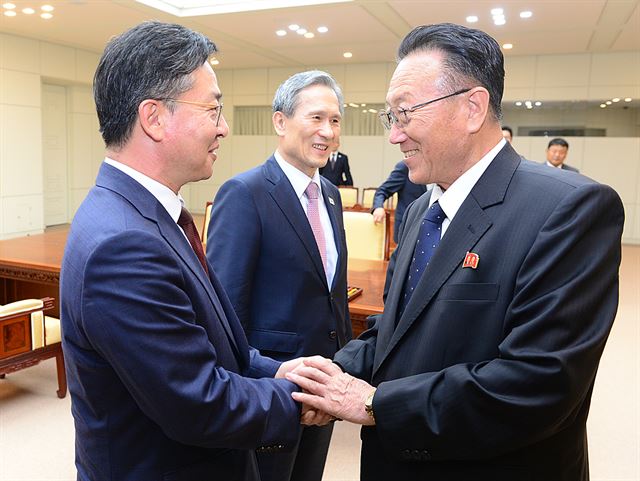 홍용표(왼쪽) 통일부장관과 김양건 북한 노동당 비서가 25일 판문점에서 남북 협상을 끝낸 뒤 환한 표정으로 두 손을 맞잡고 인사하고 있다. 김관진 국가안보실장이 표정도 어느 때보다 밝아 보인다. 통일부 제공