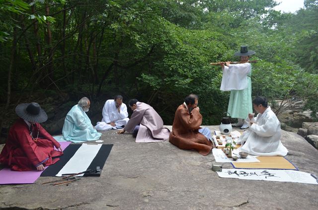 괴산바둑협회 회원들이 5일 갈은구곡 선국암에서 신선들이 바둑두는 모습을 재현하고 있다. 주변에서는 대금연주, 휘호쓰기, 전통차 시연을 하고 있다. 19일 이곳서 열리는 프로 9단들의 특별 대국도 두루마기를 입고 진행된다. 괴산군 제공