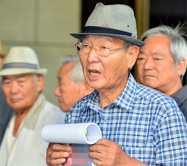 10일 오전 서울 서초구 대법원에서 허 일병의 부친 허영춘씨(76)가 아들의 시신 사진을 내보이며 판결의 부당함을 토로하고 있다. 배우한기자 bwh3140@hankookilbo.com