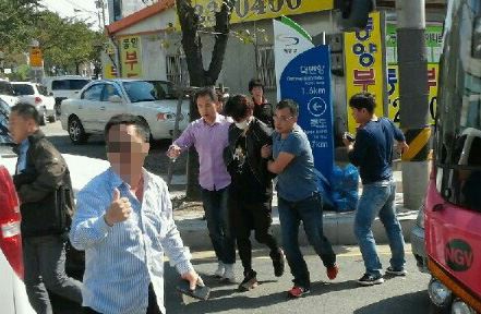 3일 오후 부산 기장군 한 교차로에서 경찰이 신호대기 중이던 택시에 타고 있던 홍모씨를 검거해 압송하고 있다. 홍씨는 이날 오전 부산 서면에 있는 한 실내사격장에 침입해 여주인을 흉기로 찌르고 권총과 실탄을 빼앗아 달아났다. 연합뉴스