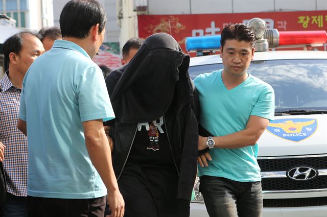 3일 오후 부산 부산진구 부산진경찰서에 이날 오전 실내사격장에 침입해 여주인을 흉기로 찌르고 권총과 실탄을 빼앗아 달아난 홍모(29)씨가 검거돼 경찰에 압송되고 있다. 연합뉴스