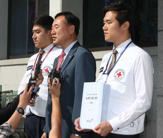 김성근 대한적십자사 국제남북국장(가운데)과 남북교류팀 직원들이 이산가족 생사확인 의뢰 명단 교환을 위해 지난달 15일 오전 서울 중구 한적 남산본사에서 나와 판문점으로 향하기에 앞서 취재진 질문에 답하고 있다. 연합뉴스