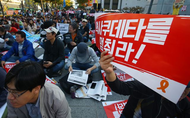 17일 오후 서울 종로구 세종로공원에서 열린 한국사교과서 국정화 저지 국민대회에서 한 참가자가 구호가 적힌 피켓을 들고 있다. 연합뉴스