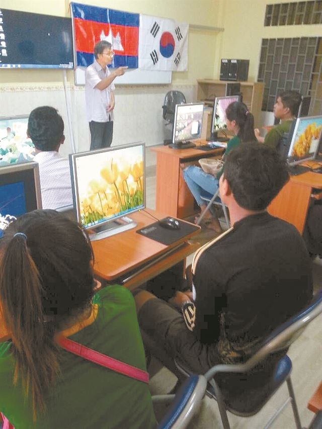 캄보디아 국기와 태극기가 나란히 걸린 깜뽕츠낭 꿈의학교 교실에서 지역 공무원들이 컴퓨터 교육을 받고 있다. 캄보디아학교세우기모임 제공.