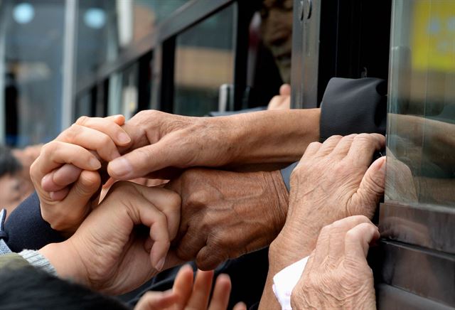 22일 강원도 고성 금강산 이산가족면회소에서 열린 제20차 남북이산가족상봉 작별상봉을 마친후 북측 가족들이 버스에 탑승한 가운데 남측 가족들이 마지막으로 손을 잡으며 눈물로 배웅하고 있다. 금강산=사진공동취재단