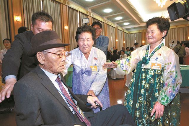 이산가족 2차 상봉 남측 최고령자인 구상연(98) 할아버지가 26일 금강산호텔에서 작별상봉을 마친 뒤 아들 형서(42)씨가 미는 휠체어에 앉아 발길을 돌리려 하자 북측의 큰 딸 송옥(71ㆍ오른쪽)씨와 작은 딸 선옥(68)씨가 애끓는 표정으로 손을 내밀며 이별을 아쉬워하고 있다. 금강산=사진공동취재단