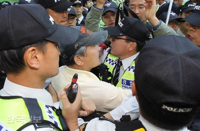 보수단체인 어버이연합 회원이 13일 오전 서울 여의도역 앞에서 열린 새정치민주연합의 친일·독재교과서 국정화 반대 서명운동 현장에서 진성준 의원을 폭행해 경찰에 연행되고 있다. 오대근기자 inliner@hankookilbo.com