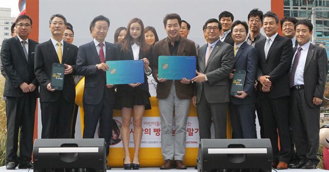 서울 청계광장에서 열린 '사랑의 빵 나눔 단말기 업무 협약식'에서 김덕수(왼쪽에서 세 번째) KB국민카드 사장, 손연재(네 번째) 리듬체조 선수, 월드비전 친선대사인 탤런트 박상원(다섯 번째)씨 등 관계자들이 기념촬영을 하고 있다. KB국민카드 제공