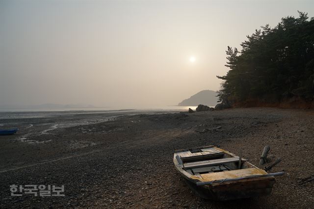 썰물로 드러난 바다를 걸어가는 아라메길의 호리 옻샘 주변 구간. 해질녘 뻘에 올라앉은 허름한 목선이 깊은 울림을 전해준다. 이성원기자 sungwon@hankookilbo.com