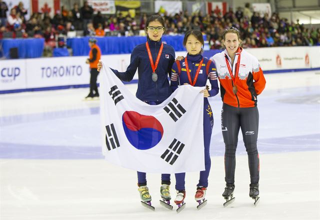 9일(한국시간) 캐나다 토론토에서 열린 2015-2016 국제빙상경기연맹(ISU) 쇼트트랙 월드컵 2차 대회 여자 1,500ｍ에서 우승한 최민정(가운데)이 2위 심석희(왼쪽)와 태극기를 들고 포즈를 취하고 있다. 오른쪽은 3위 마리안 생겔라(캐나다). 토론토=신화 연합뉴스