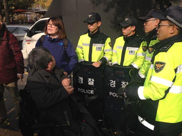 11일 오전 기자회견에 참석하려는 김재익 소장을 경찰들이 막고 서 있다. 한국장애인자립생활센터총연합회 제공